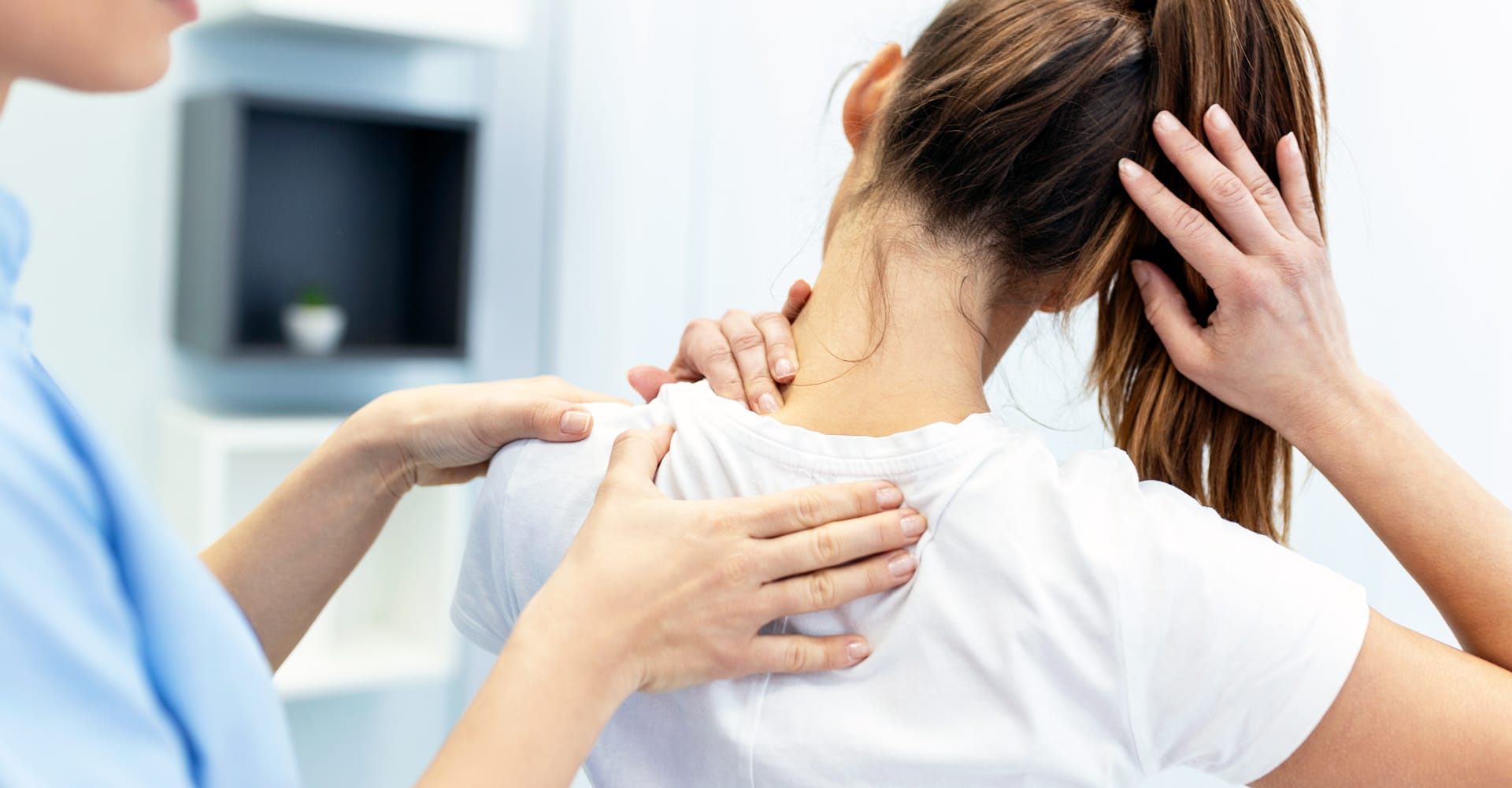Close-up of a health care provider helping a patient with what appear to be neck and shoulder issues
