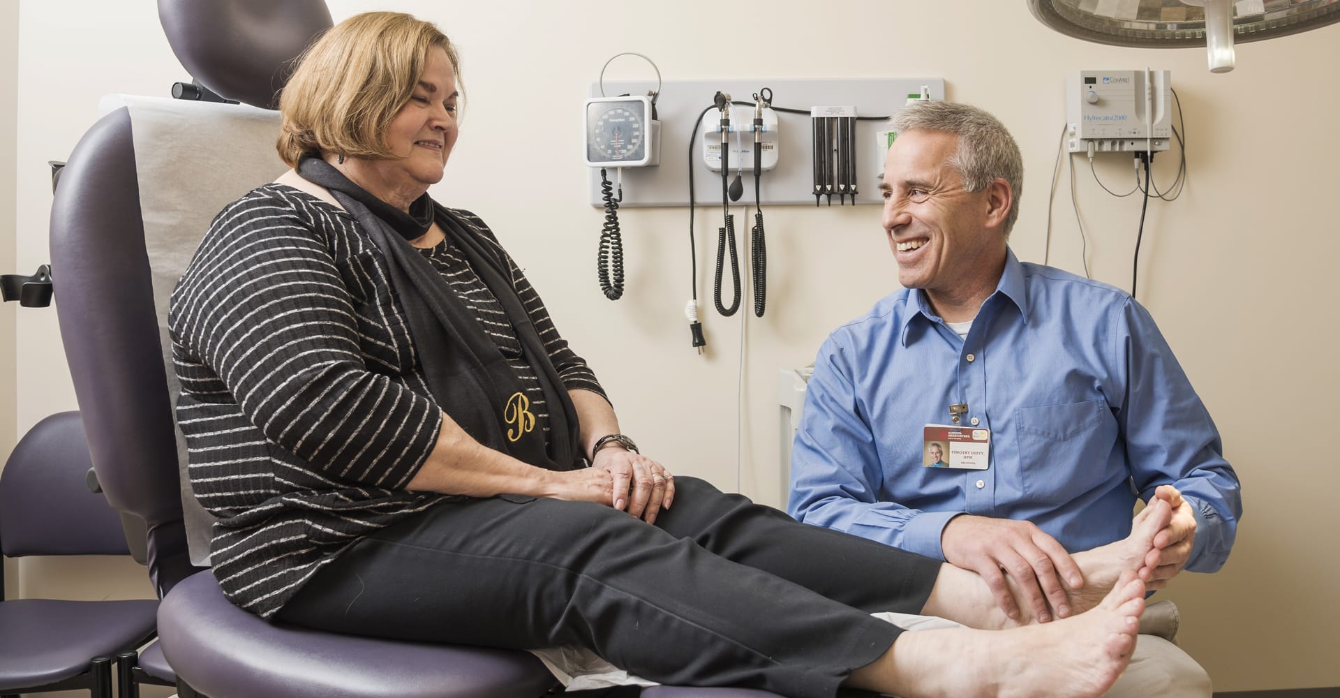 A health care provider examining the feet of a seated patient