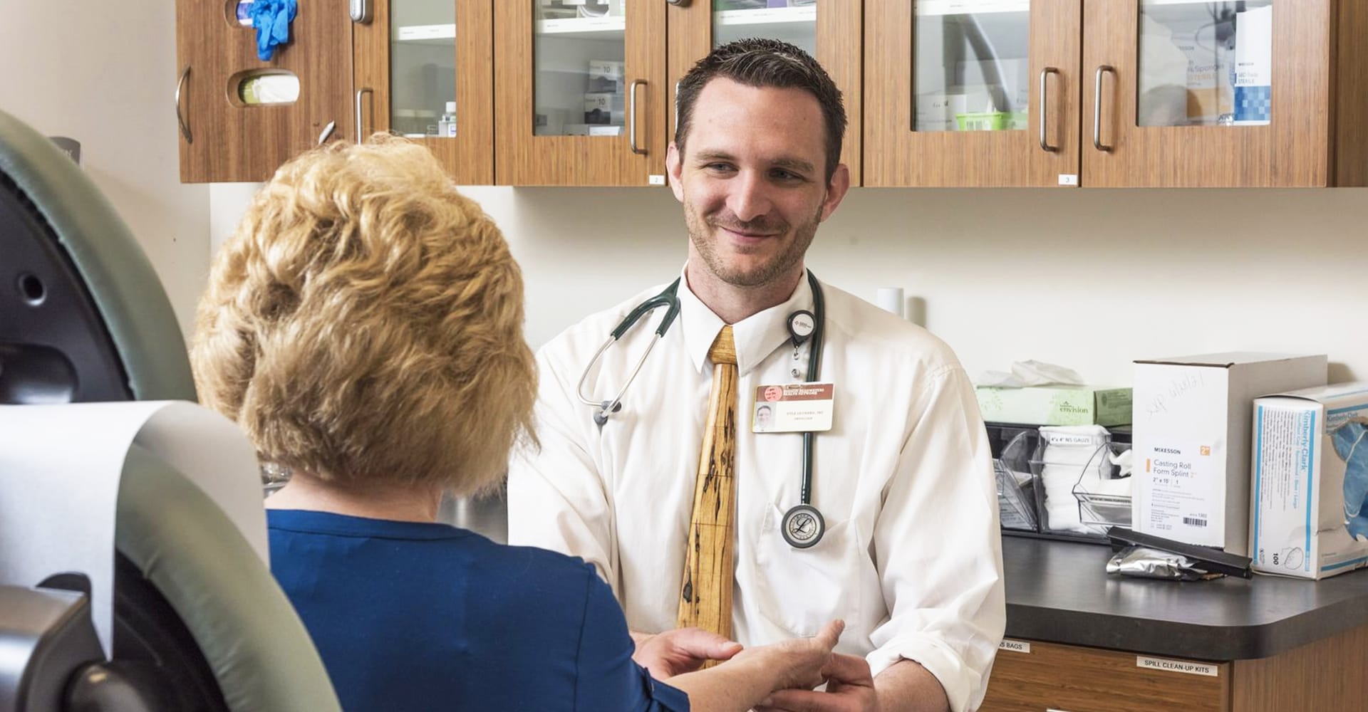 A health care provider and seated patient in an exam setting