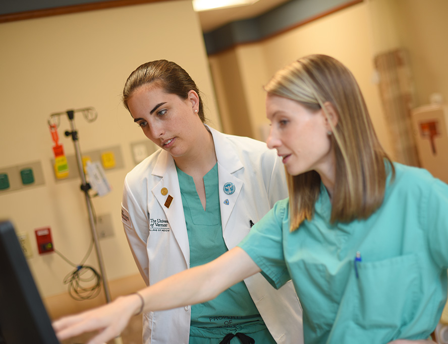 A doctor showing a medical student something on a computer
