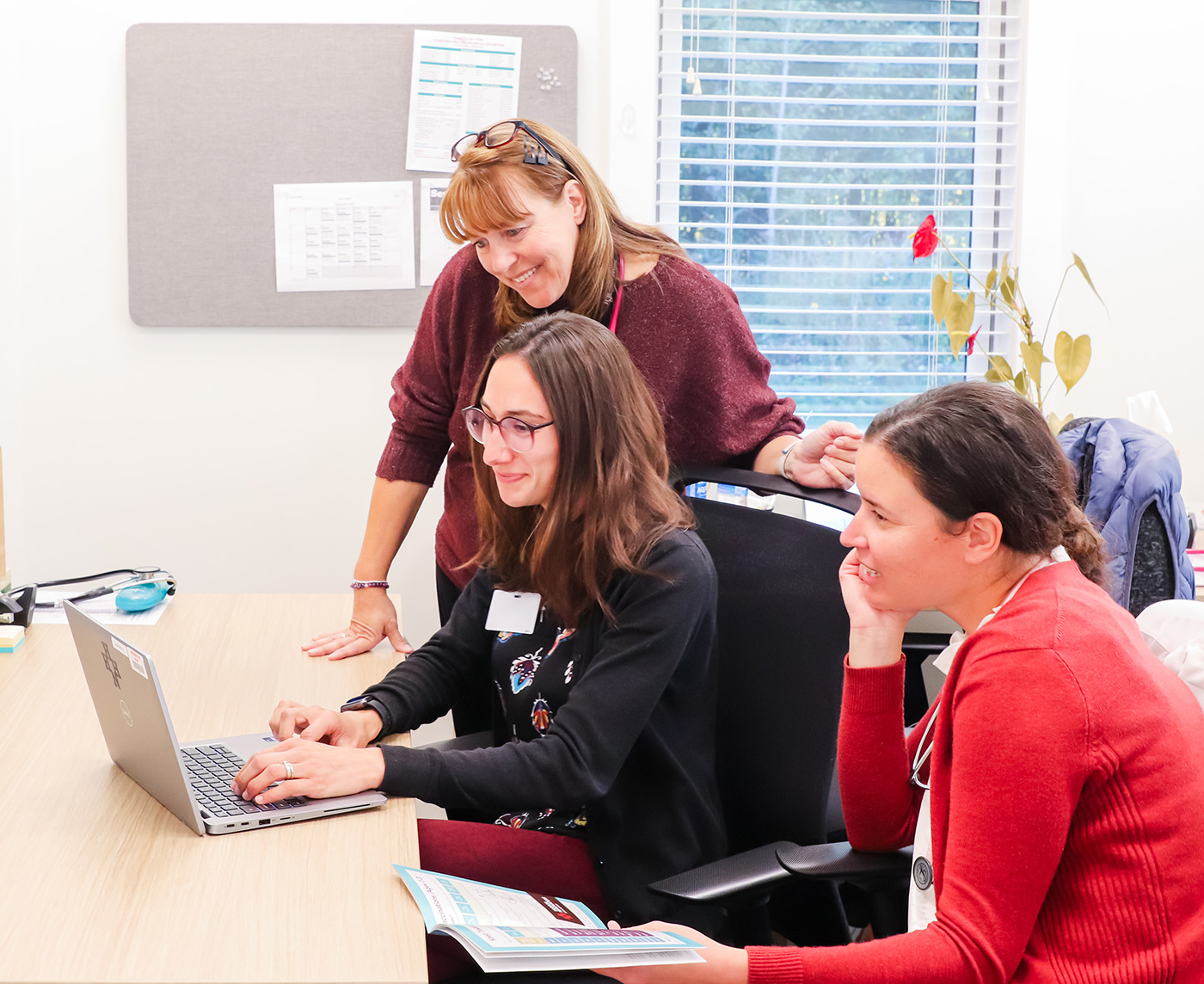 Three health care providers looking at a computer